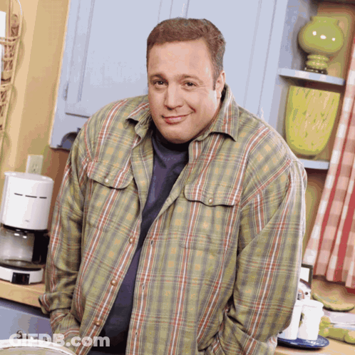 A Man In A Plaid Shirt Stands In Front Of A Coffee Maker GIF