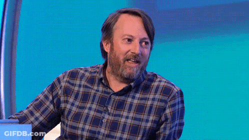 A Man In A Plaid Shirt Stands In Front Of A Purple Background That Says I Am Not Okay GIF