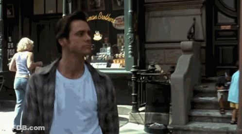 A Man In A Plaid Shirt Stands In Front Of A Store Called Man Brothers GIF
