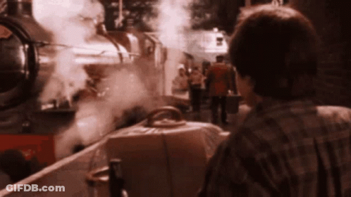 A Man In A Plaid Shirt Stands In Front Of A Train That Has The Number 5 On The Front GIF