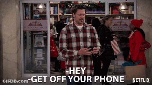 A Man In A Plaid Shirt Stands In Front Of An Alexander & Vaughn Store GIF