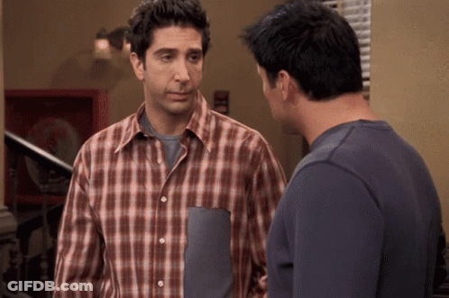 A Man In A Plaid Shirt Stands Next To Another Man In A Blue Shirt GIF
