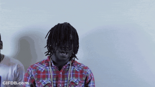 A Man In A Plaid Shirt Stands Next To Another Man In A White Shirt GIF
