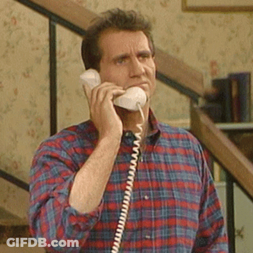 A Man In A Plaid Shirt Talking On A Phone GIF