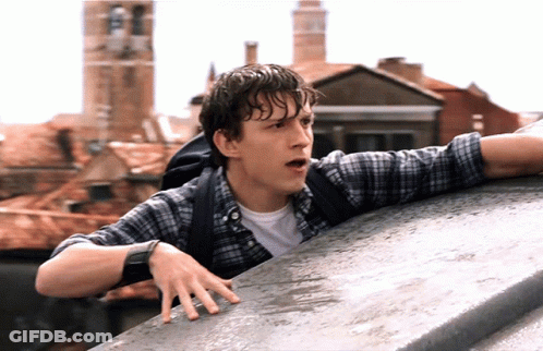 A Man In A Plaid Shirt With A Backpack Leaning Over A Ledge GIF
