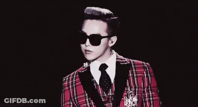 A Man In A Plaid Suit And Sunglasses Is Pointing At Something . GIF