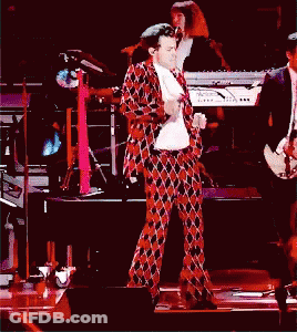 A Man In A Plaid Suit Is Dancing On A Stage GIF