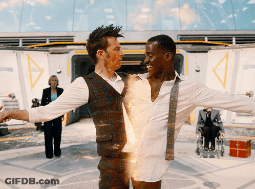 A Man In A Plaid Vest Is Holding A Man In A White Shirt GIF
