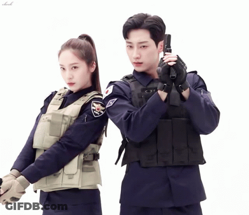 A Man In A Police Uniform Holds A Gun Next To A Woman In A Police Uniform GIF