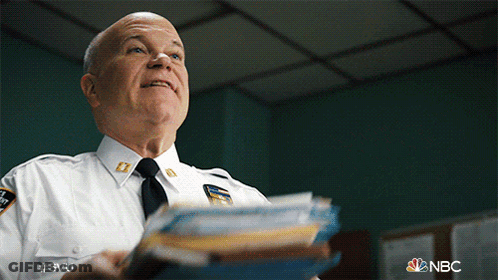 A Man In A Police Uniform Is Holding A Stack Of Papers In His Hand GIF