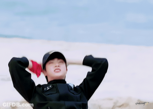 A Man In A Police Uniform Is Laying In The Sand With His Arms Outstretched .. GIF