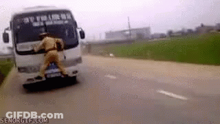 A Man In A Police Uniform Is Pushing A Bus Down A Road . GIF