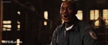 A Man In A Police Uniform Is Standing In A Dark Room Holding His Fist Up . GIF