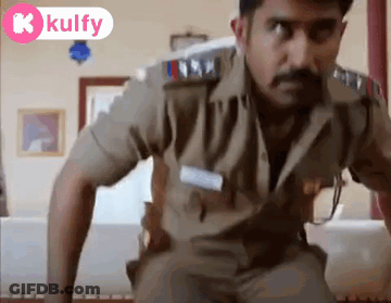 A Man In A Police Uniform Is Standing In A Living Room Looking At The Camera . GIF
