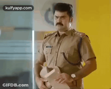 A Man In A Police Uniform Is Standing In A Room Holding A Hat . GIF