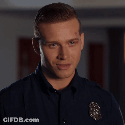 A Man In A Police Uniform Is Standing In Front Of A Box GIF