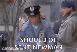 A Man In A Police Uniform Is Standing Next To Another Man And Holding A Box . GIF