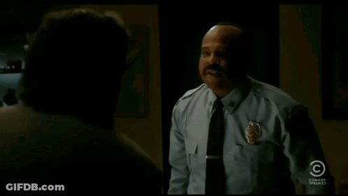 A Man In A Police Uniform Says " I 'Ll Take It " In A Dark Room GIF