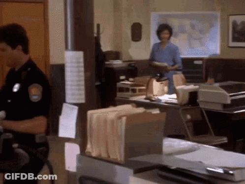 A Man In A Police Uniform Stands In A Police Station GIF