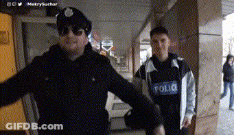 A Man In A Police Uniform Stands Next To Another Man GIF