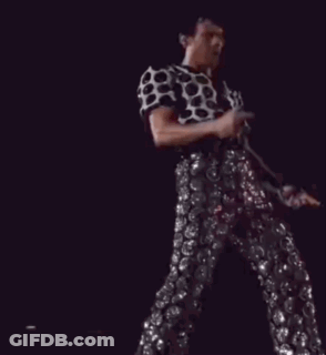 A Man In A Polka Dot Shirt And Sequined Pants Is Dancing On Stage GIF