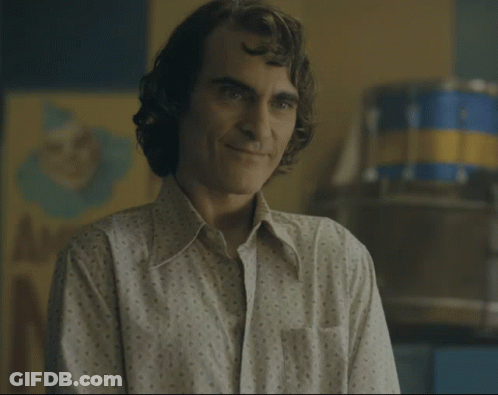 Man In Polka Dot Shirt Smiling In Front Of A Sign GIF