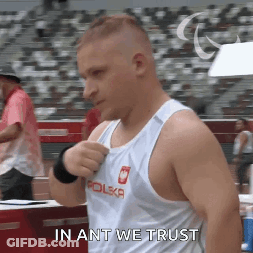A Man In A Polska Tank Top Is Standing In Front Of A Crowd And Saying In Ant We Trust GIF