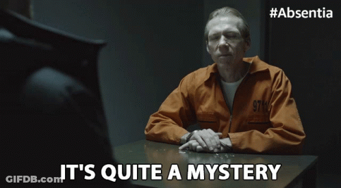 A Man In A Prison Uniform Sits At A Table With The Words It 'S Quite A Mystery Below Him GIF