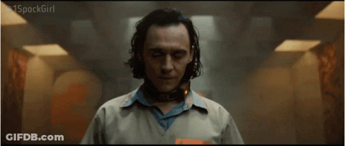 A Man In A Prison Uniform With A Collar Around His Neck Is Standing In A Hallway . GIF