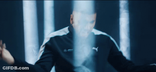 A Man In A Puma Jacket Stands In Front Of A Blue Light GIF
