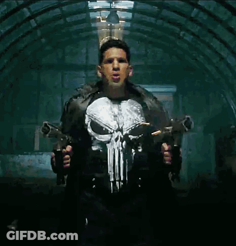 A Man In A Punisher Costume Holds Two Guns GIF