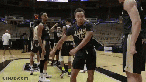 A Man In A Purdue Shirt Is Dancing On A Basketball Court . GIF