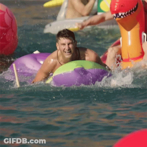 A Man In A Purple And Green Raft Is Splashing In The Water GIF