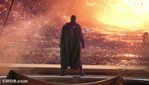 A Man In A Purple Cape Is Standing In Front Of A Fire GIF