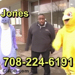 A Man In A Purple Dinosaur Costume Stands Next To A Yellow Duck Costume GIF