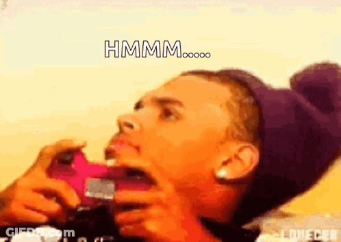 A Man In A Purple Hat Is Taking A Picture With His Mouth Open And The Words Hmmm Written Above Him GIF