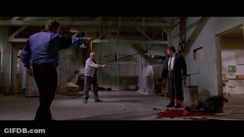 A Man In A Purple Jacket Is Pointing A Gun At Another Man GIF