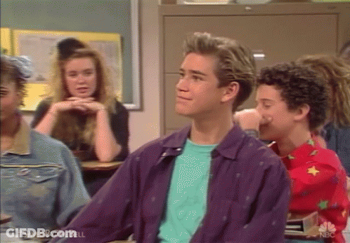 A Man In A Purple Jacket Is Sitting In A Classroom With Other Students GIF
