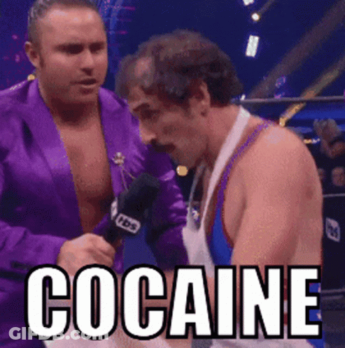 A Man In A Purple Jacket Is Talking Into A Microphone While Another Man Looks On With The Word Cocaine Written In White GIF
