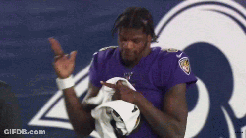 A Man In A Purple Jersey Is Standing In Front Of A Rams Logo . GIF