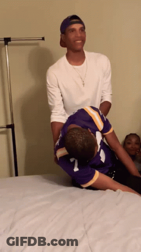 A Man In A Purple Jersey With The Number 7 On It Is Laying On Another Man 'S Back GIF