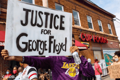 A Man In A Purple Lakers Shirt Holds A Sign That Says Justice For George Floyd GIF