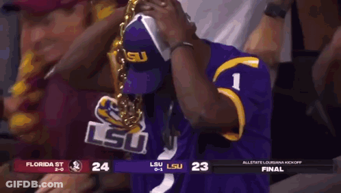 A Man In A Purple Lsu Jersey Is Wearing A Gold Chain Around His Neck .. GIF