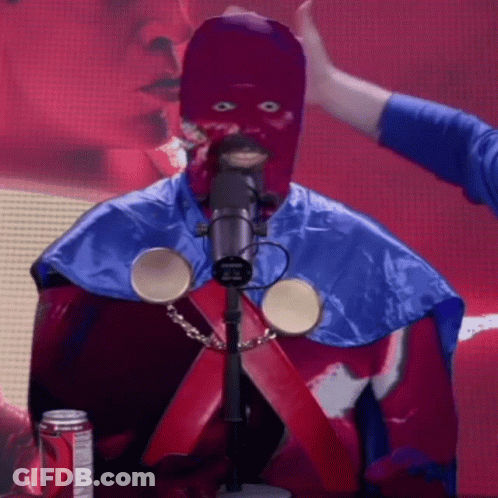 A Man In A Purple Mask Is Standing In Front Of A Microphone With A Can Of Dr Pepper In The Background GIF