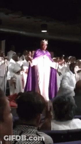 A Man In A Purple Robe And Crown Is Standing In Front Of A Crowd GIF