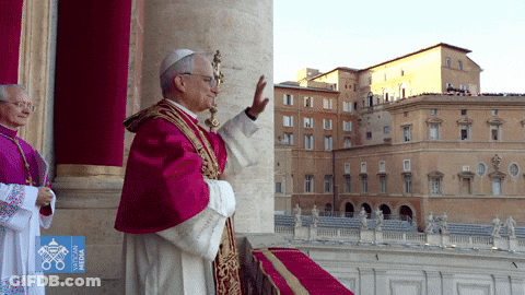 A Man In A Purple Robe Is Standing In Front Of A Building With The Word Vatican On It GIF