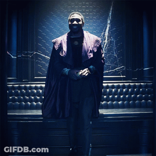 A Man In A Purple Robe Stands In Front Of A Blue Wall GIF
