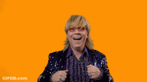 A Man In A Purple Sequined Jacket Holds His Hands Up In The Air With The Words Swipe Up Below Him GIF