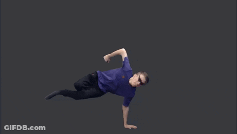A Man In A Purple Shirt And Black Pants Is Doing A Handstand On A Black Background . GIF