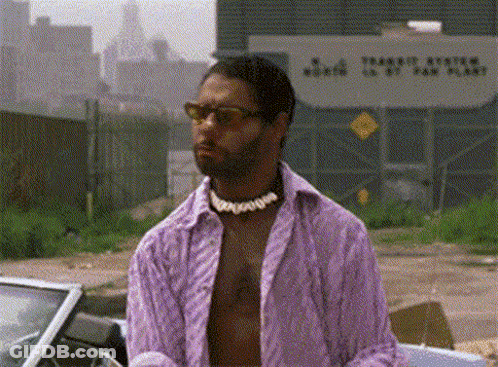 A Man In A Purple Shirt And Sunglasses Is Standing In Front Of A Car . GIF